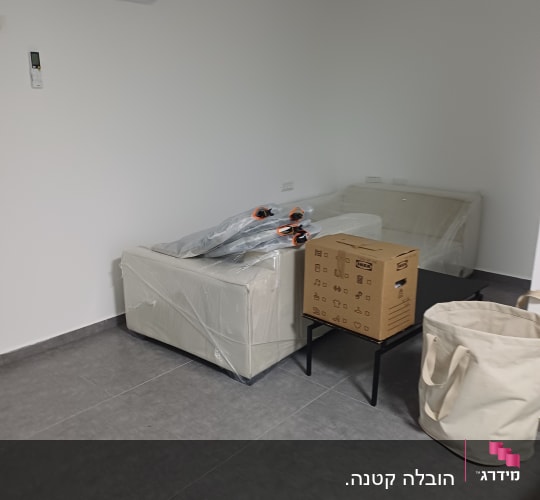 חדר עם ספה מכוסה בניילון ומזגן על הקיר